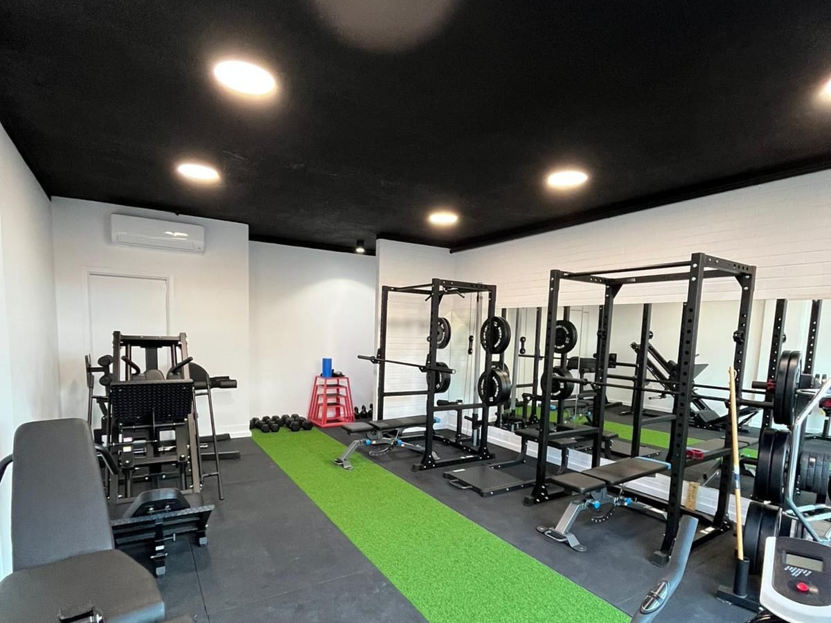 The SportsFit Gladesville gym floor with squat racks, plates and a green turf strip