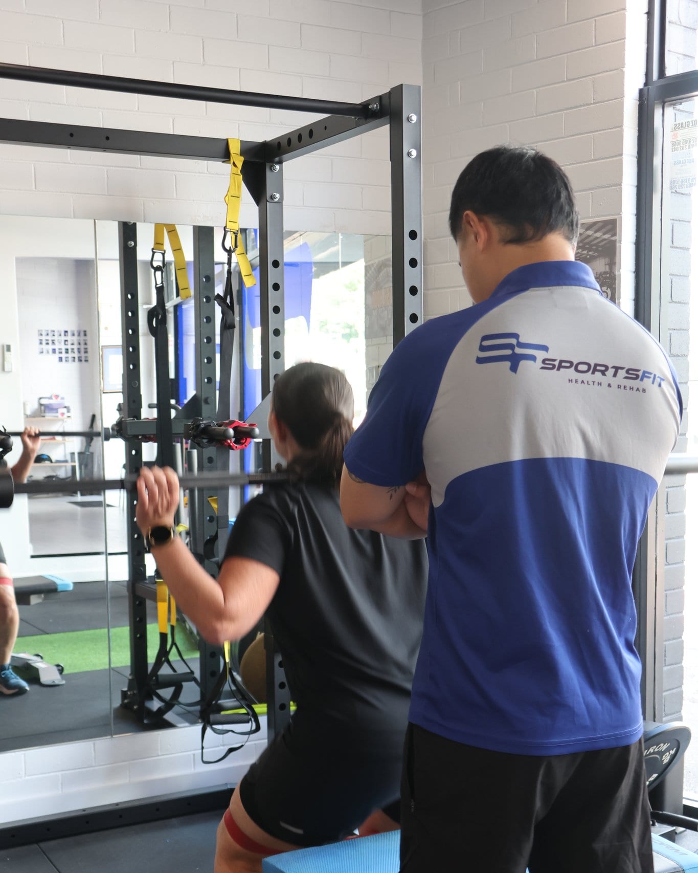 SportsFit physiotherapist supervising a kneeling band exercise at the Gladesville clinic